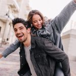 Excited man in black denim jacket chilling with girlfriend. Outdoor photo of happy couple exploring city.