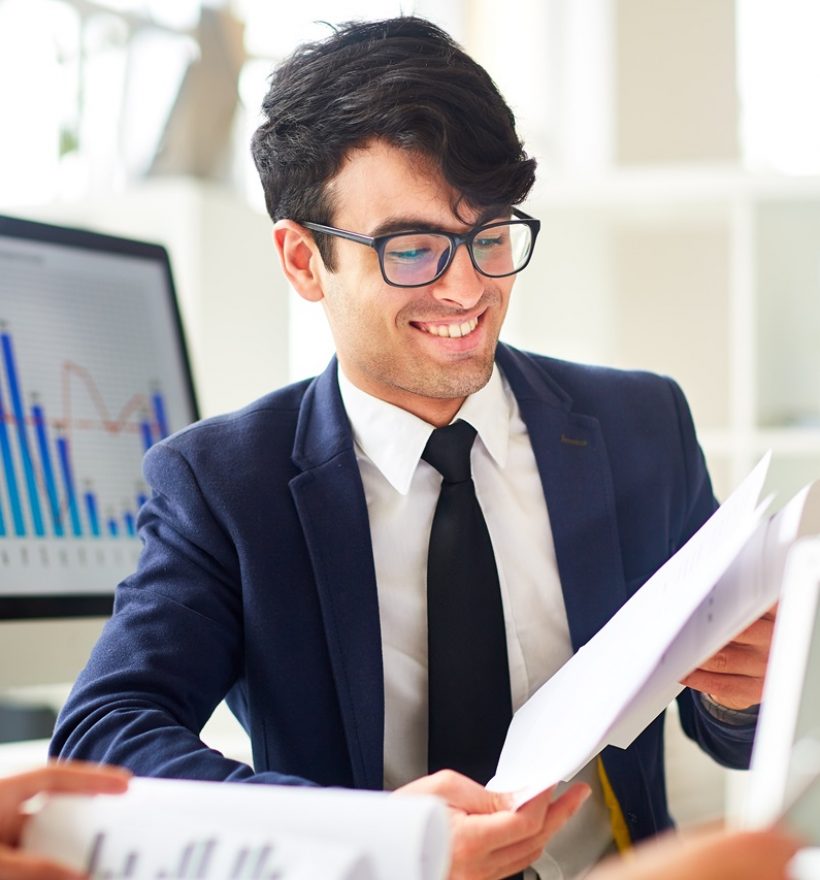 Young financier reading documents and discussing financial data with colleague